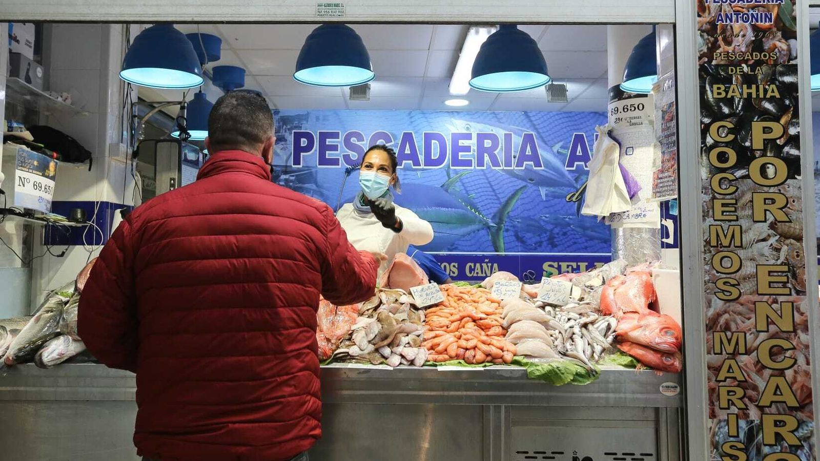 Una pescadera da la vuelta a un cliente tras la compra, en el Mercado de San Antonio.