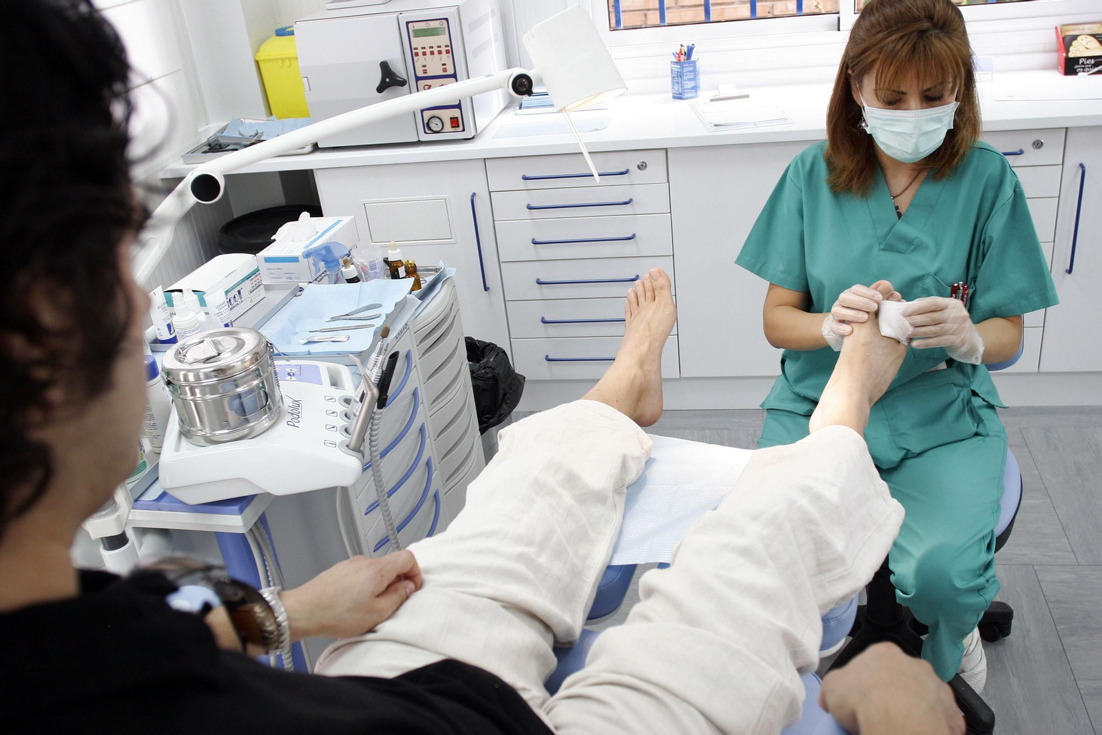 Una podóloga atiende a un paciente en su clínica.