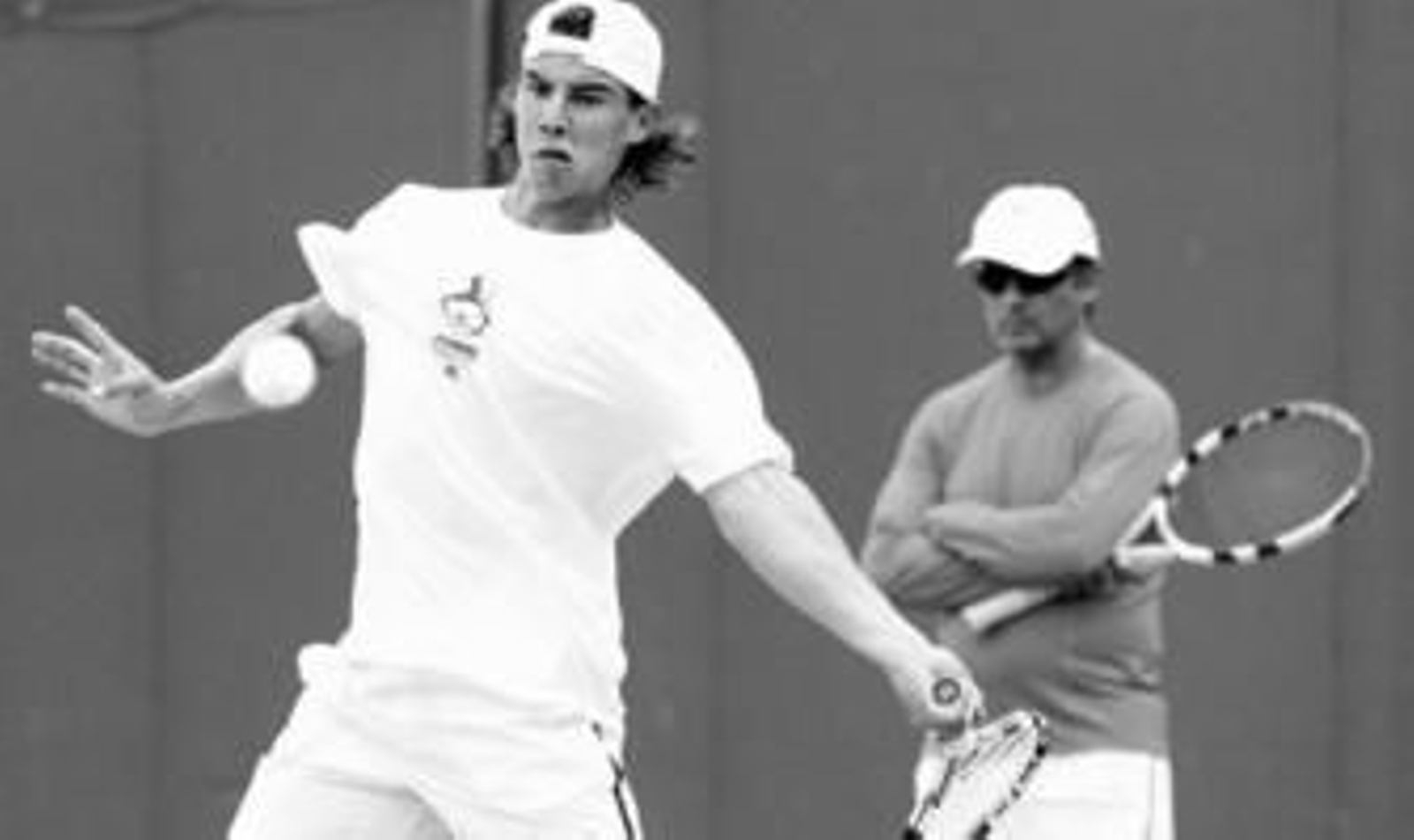 Nadal, con su tío Toni tras él asesorándolo, golpea una bola de derechas durante el entrenamiento matinal que realizó en el All England Club.