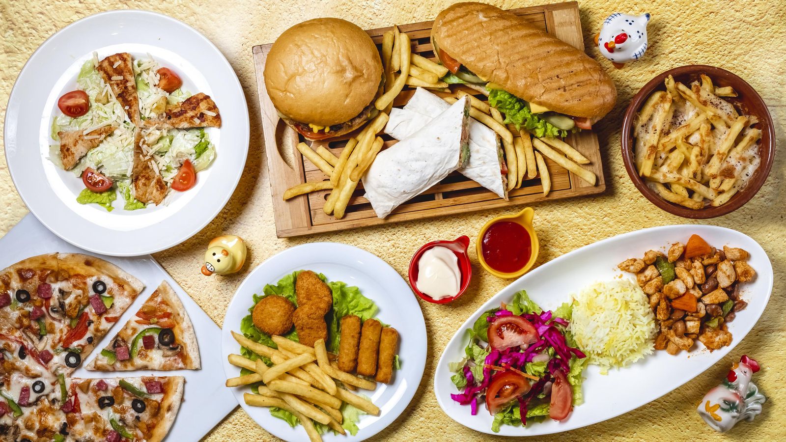 top-view-fast-food-mix-hamburger-doner-sandwich-chicken-nuggets-rice-vegetable-salad-chicken-sticks-caesar-salad-mushrooms-pizza-chicken-ragout-french-fries-mayo