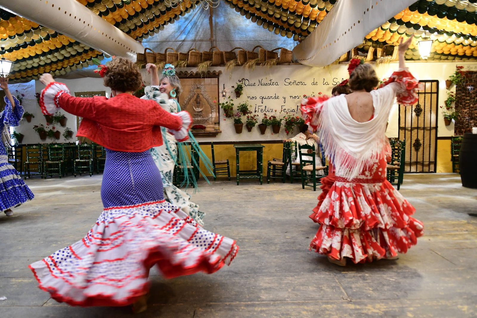 Varias mujeres bailan sevillanas en la caseta La Reja.