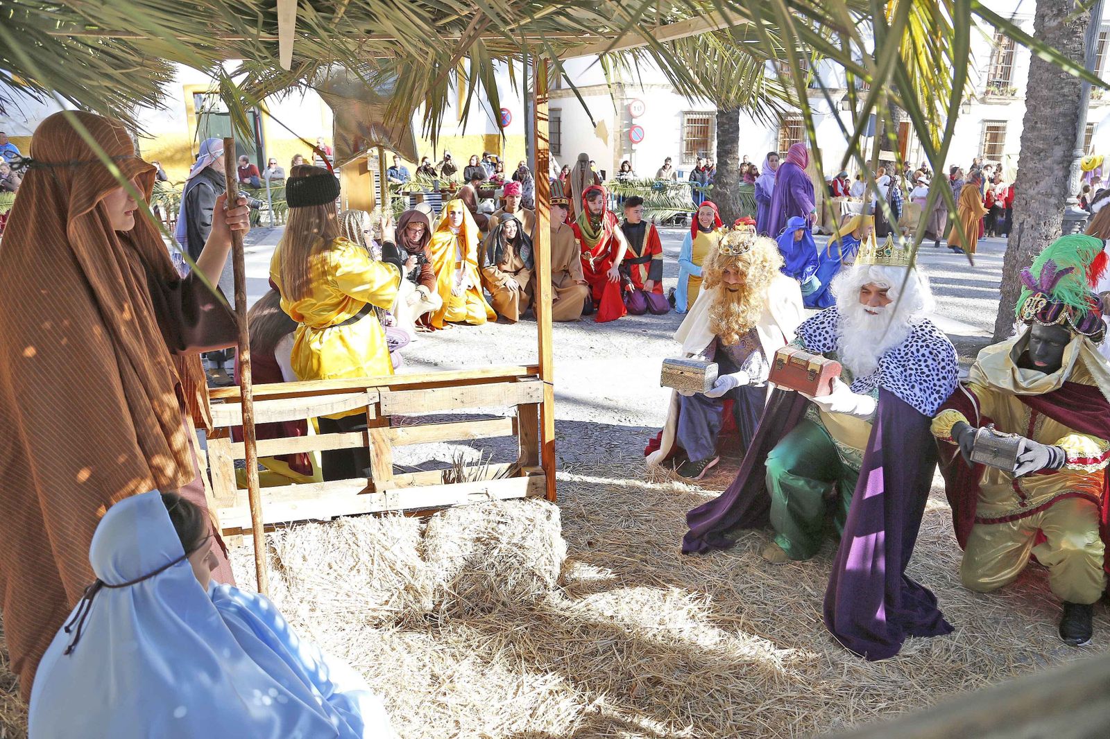 Niños y adultos escenifican la entrega de regalos de los Reyes Magos.