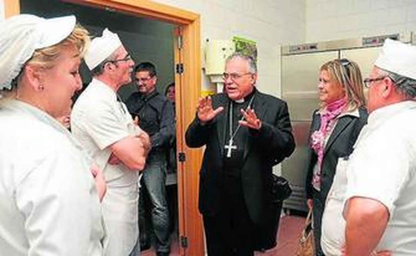 El obispo charla con trabajadores del equipo de cocina.