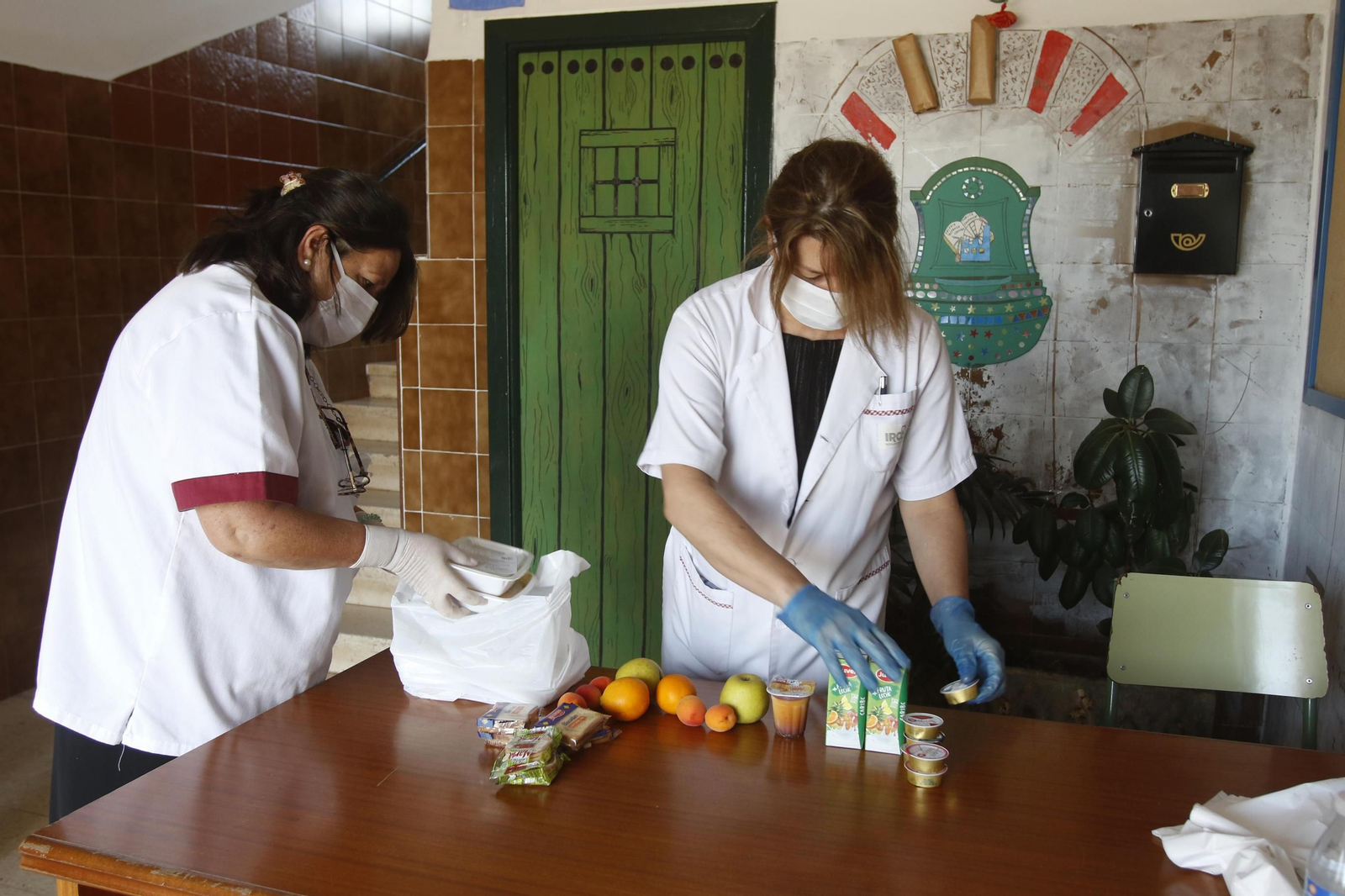 Dos operarias preparan los alimentos para los niños en un colegio.