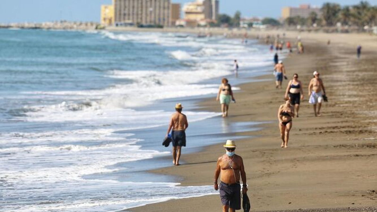 Malagueños pasean por una playa de la capital.