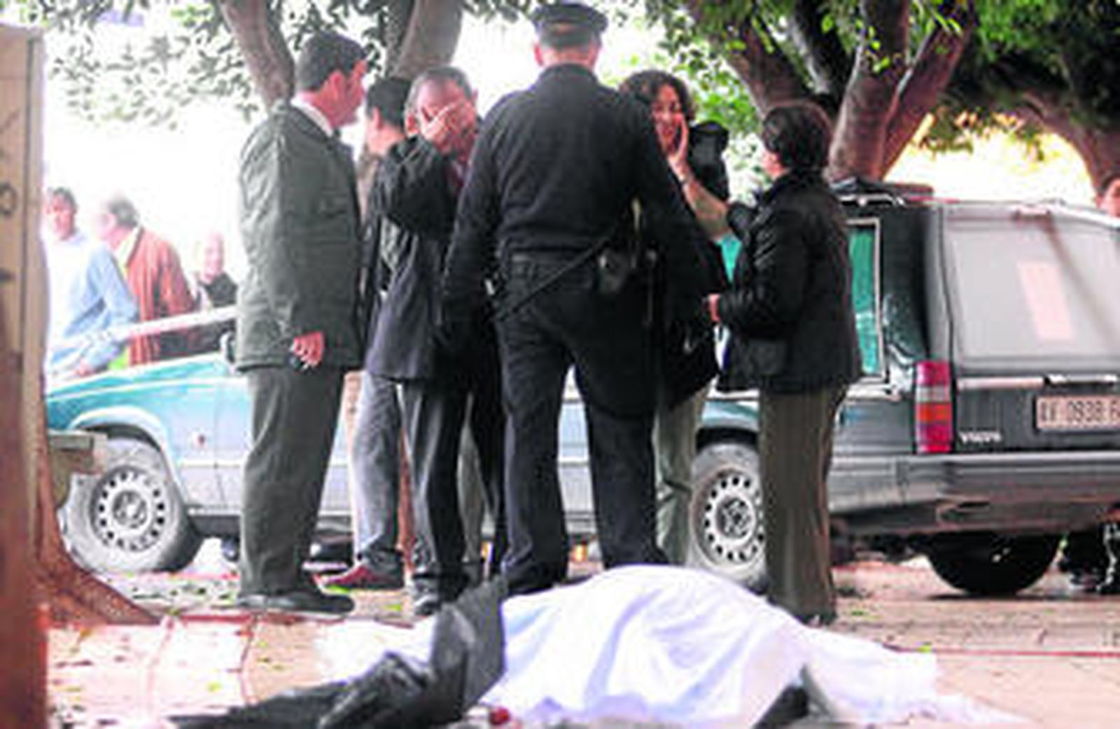 Agentes de Policía, ayer, intentan consolar a dos familiares de la fallecida, con el cuerpo aún presente de la víctima en el suelo.