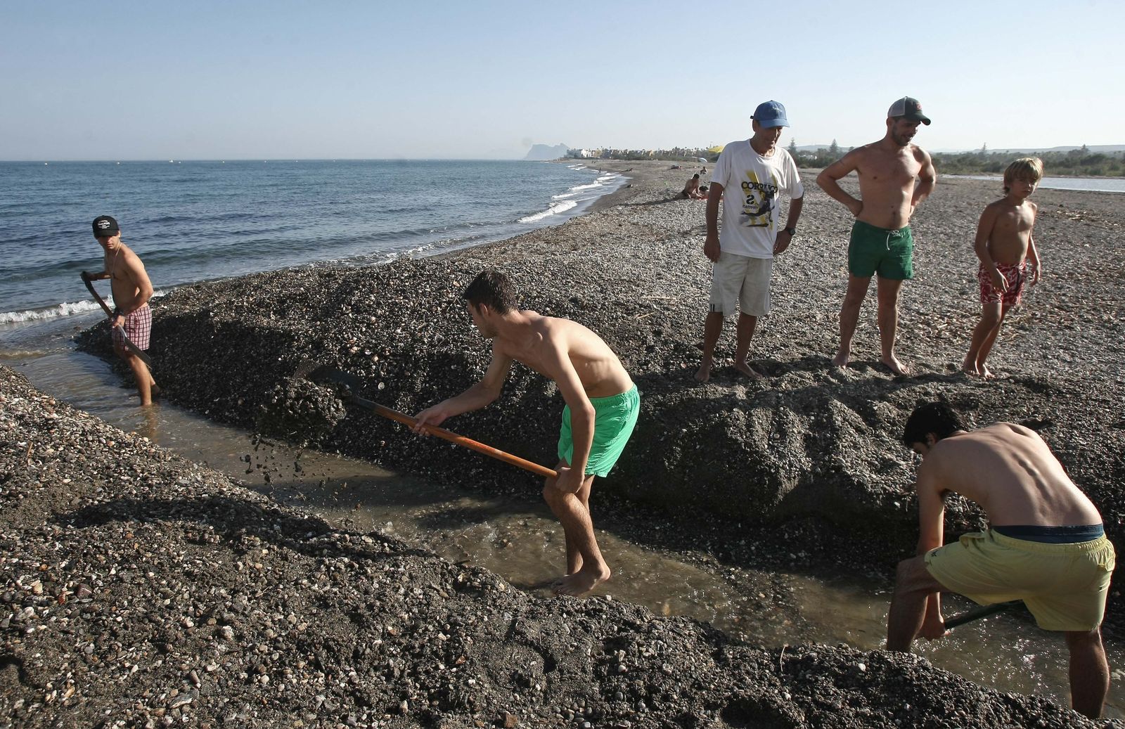 Varias personas abren con palas la bocana del río Guadiaro en una actuación promovida por los vecinos, el pasado mes de julio.