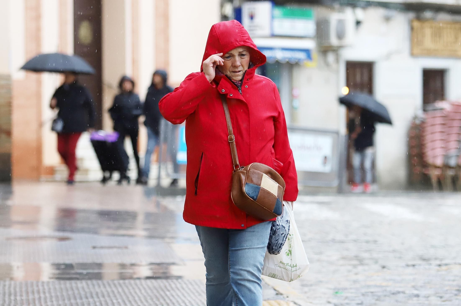 Una mujer se protege del frío y la lluvia en el centro de la capital
