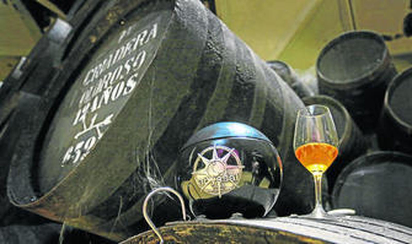 El original envase esférico de Abyssal, junto a una copa y las botas de oloroso con la que se elabora el primer 'vodka' que tiene su origen en un vino.