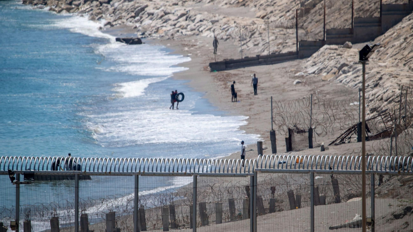 Un gendarme marroquí ayuda a un niño a salir del agua.