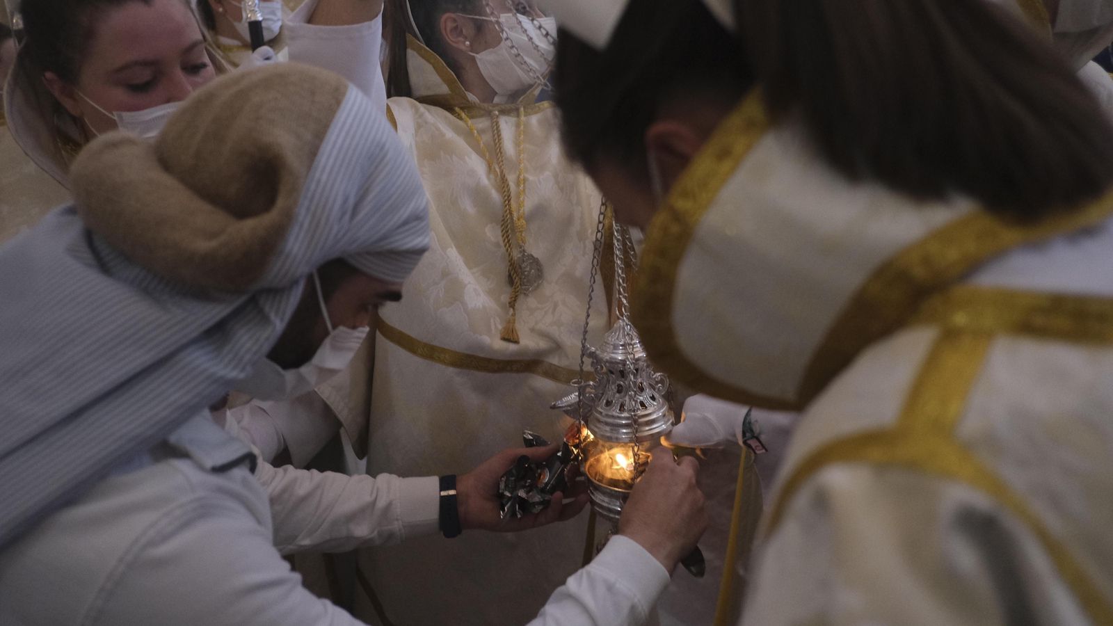 Un costalero prepara el incienso antes de la salida.