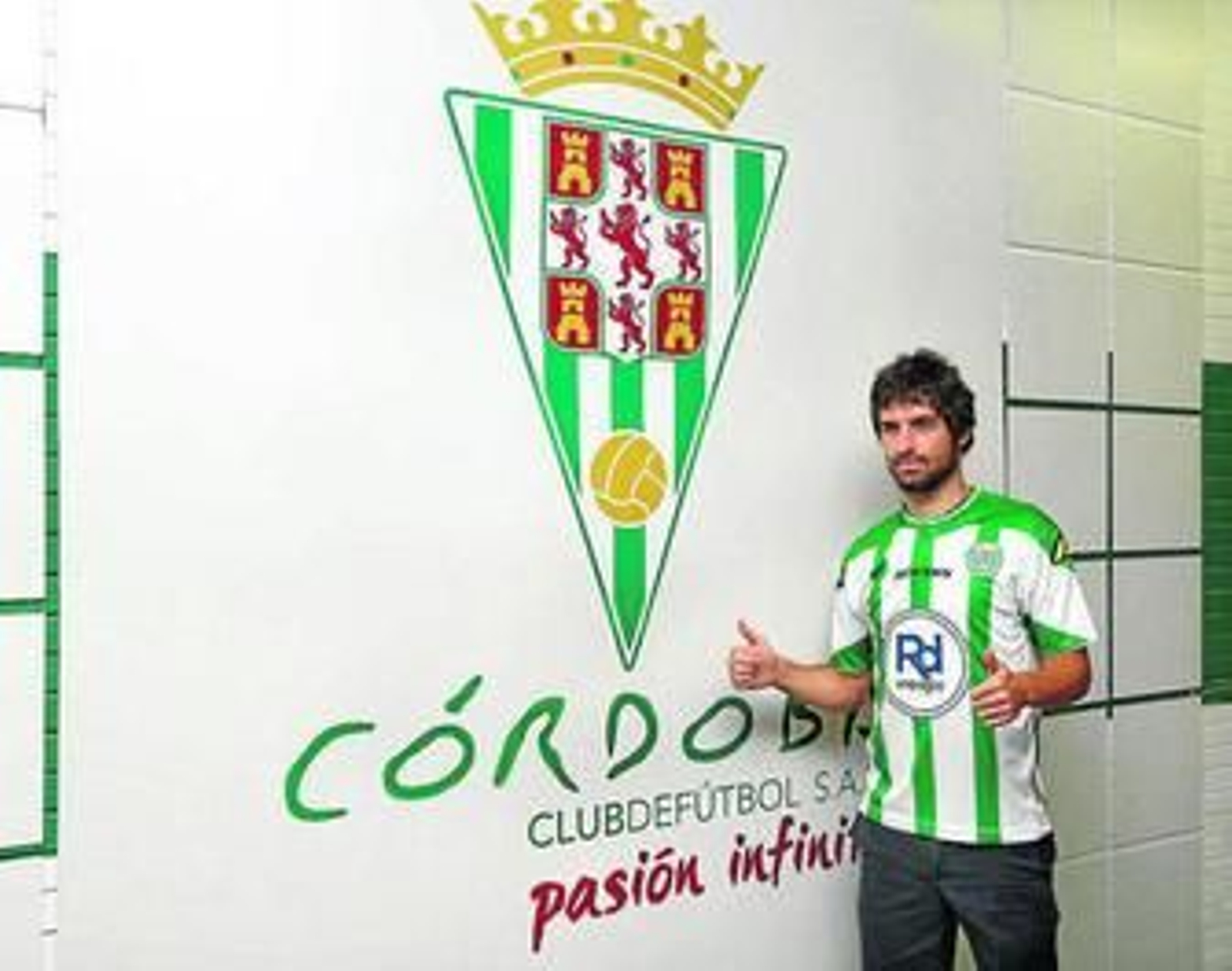 Víctor Pérez posa con la camiseta blanquiverde junto al escudo del Córdoba en el acto de su presentación.