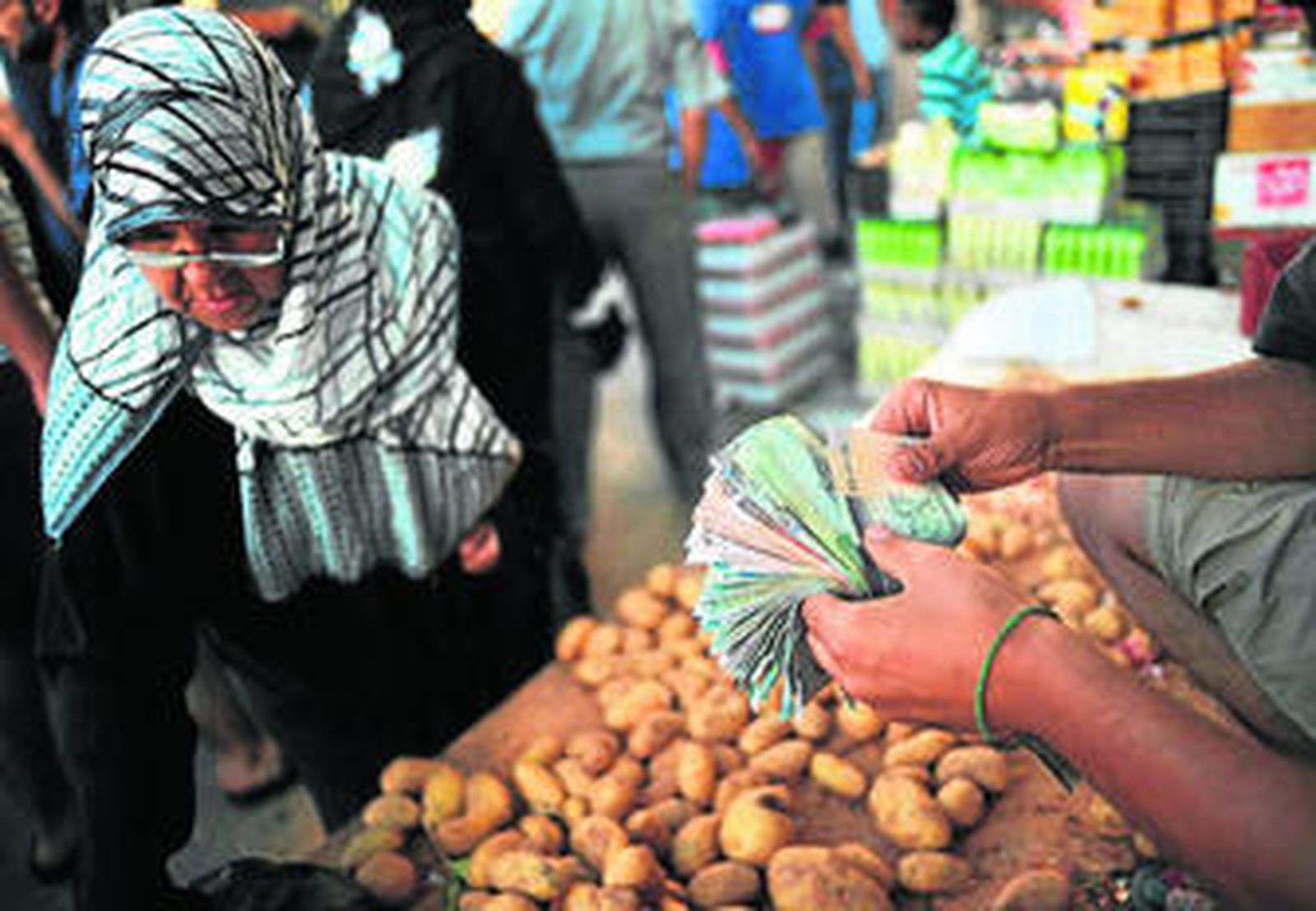 Un vendedor de patatas cuenta dinero ante una mujer en Rashid Street, en el centro de Trípoli.