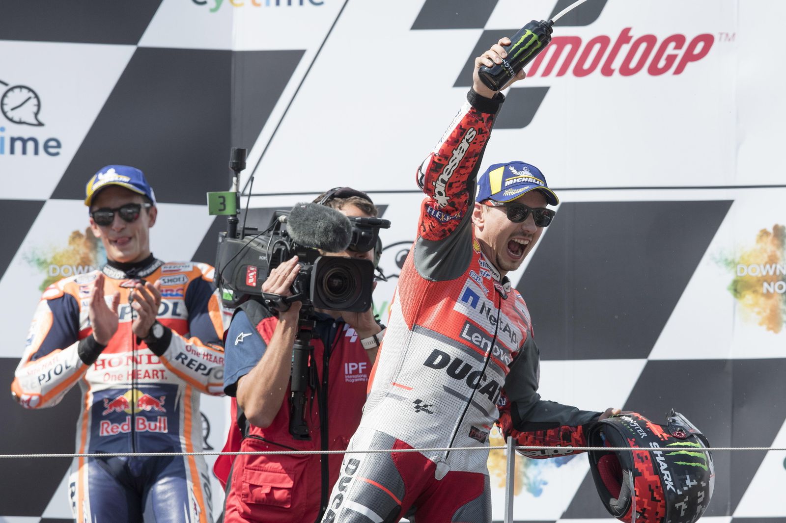 Lorenzo celebra su victoria, con Márquez aplaudiendo al fondo.