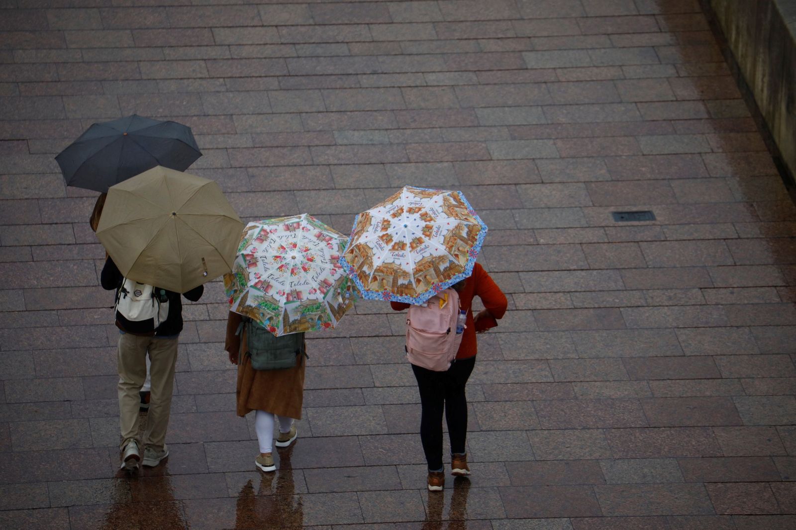 Varias personas se resguardan de la lluvia en Córdoba con paraguas.