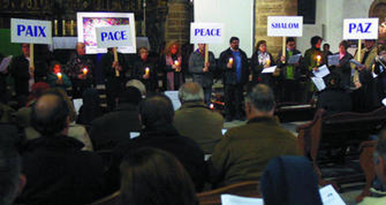 Carteles pidiendo la paz en diferentes idiomas, anoche ante el altar mayor de la iglesia de Santa Cruz.