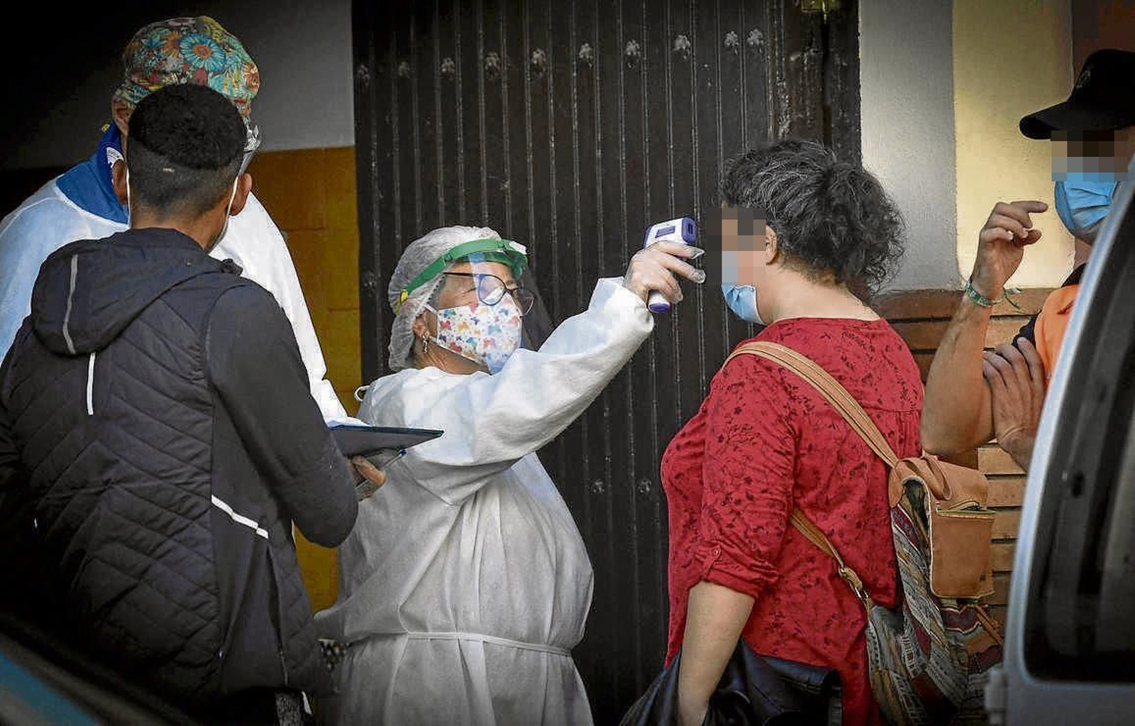 Atender y evitar contagios. El personal del comedor toma la temperatura a los usuarios.