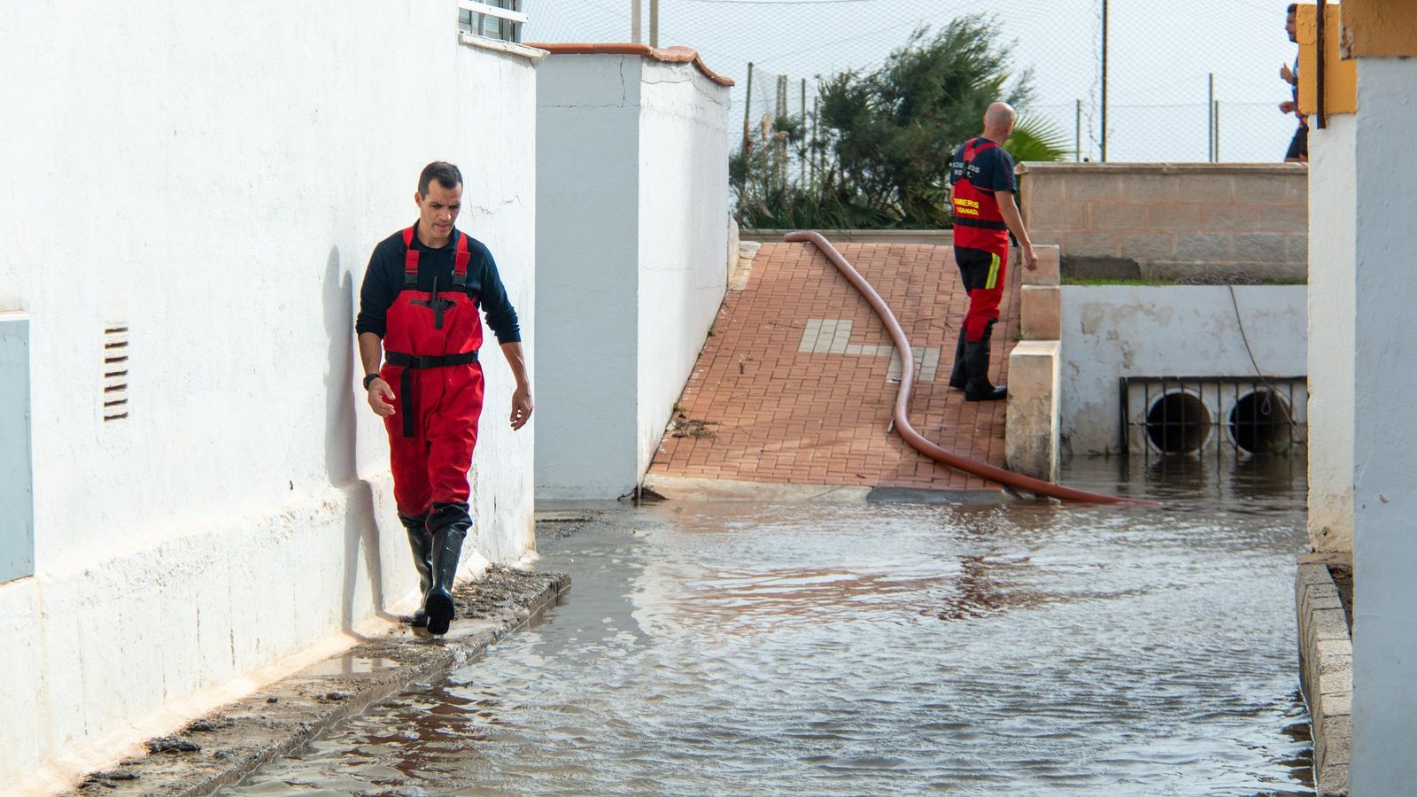 Dos bomberos trabajan achicando agua de distintos puntos de la ciudad tras el paso de la DANA