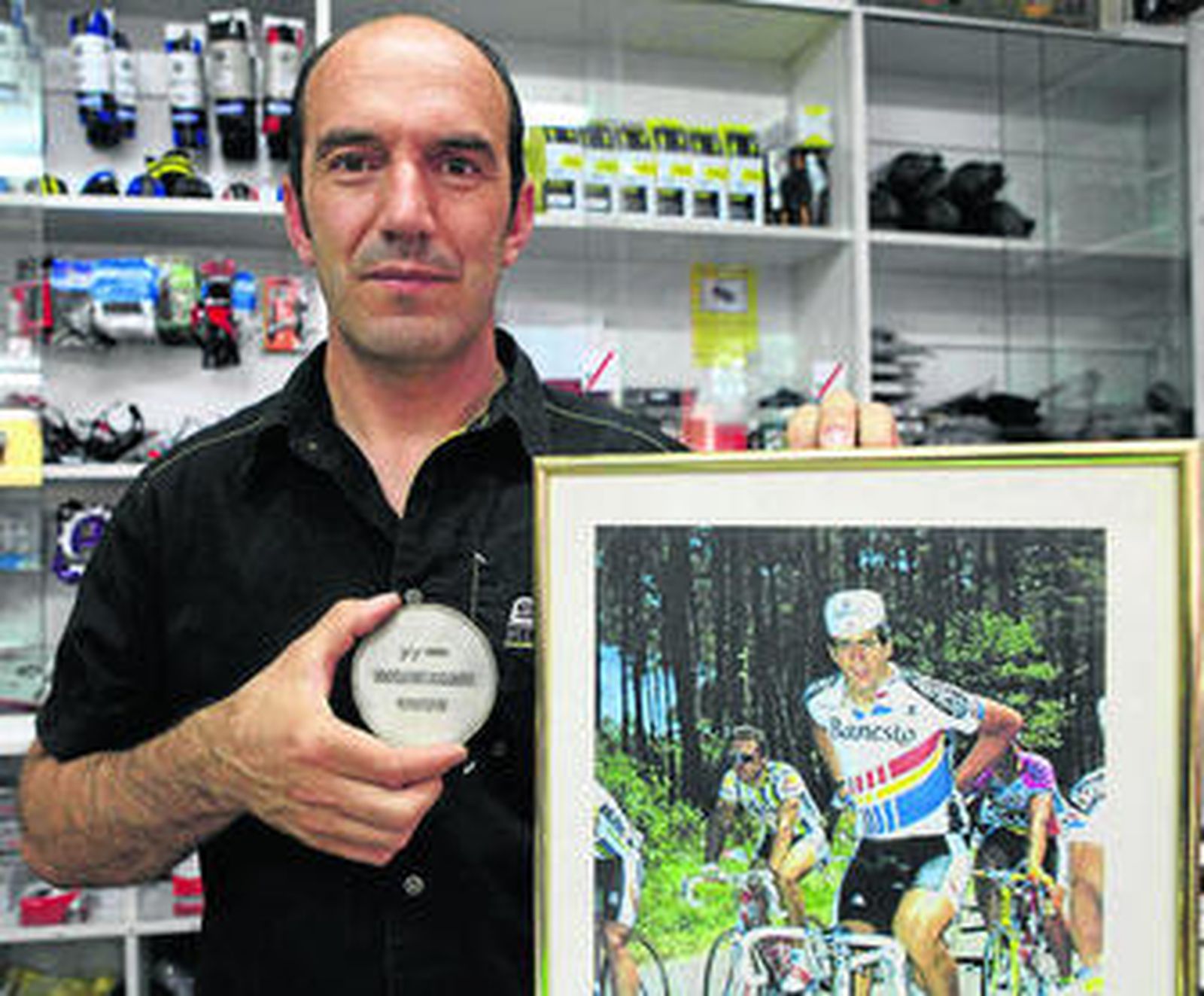 Jesús Rosado posa con la medalla del Tour y una foto de Indurain en su tienda de bicicletas en Ronda.