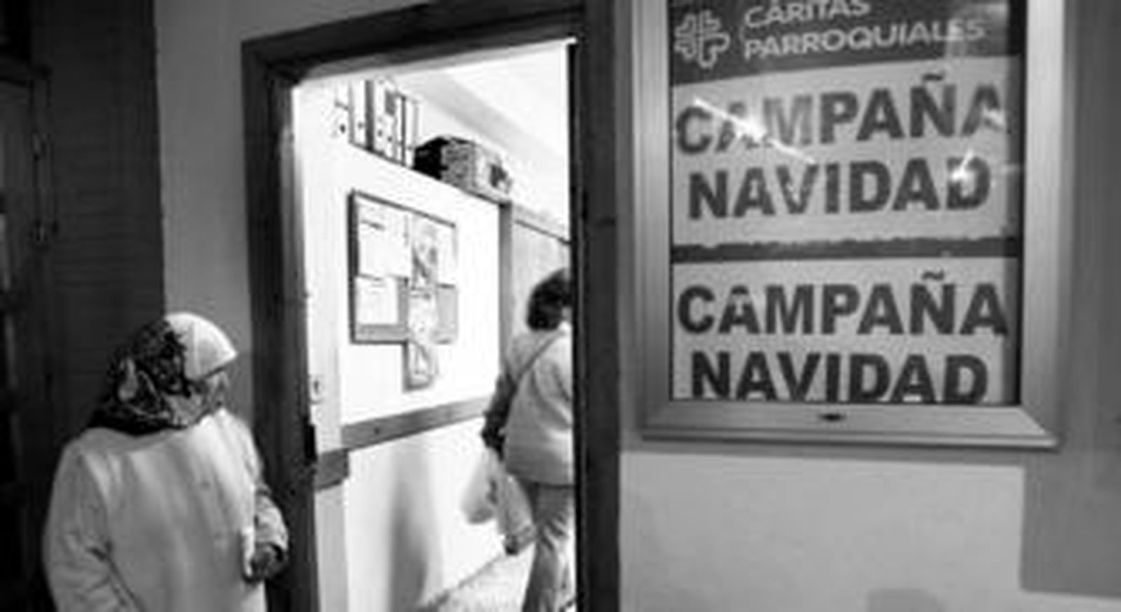 Una mujer mira hacia el interior de la sede de Cáritas Parroquiales en la parroquia del Carmen y San Marcos, donde se prepara la campaña de Navidad.