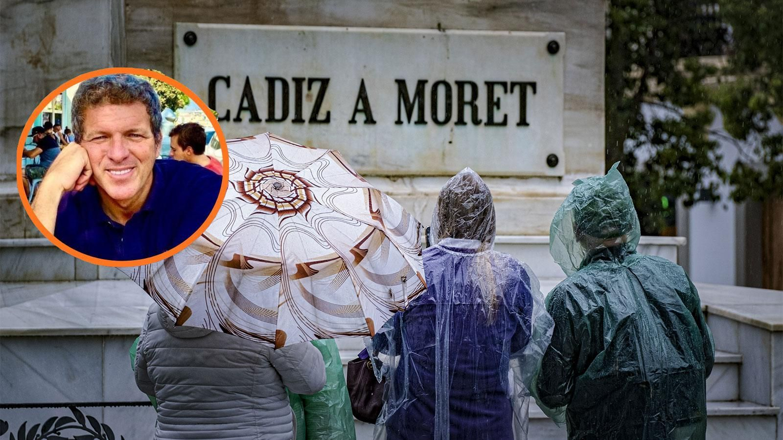 Unos turistas bajo la lluvia, ante el monumento a Moret en Cádiz.