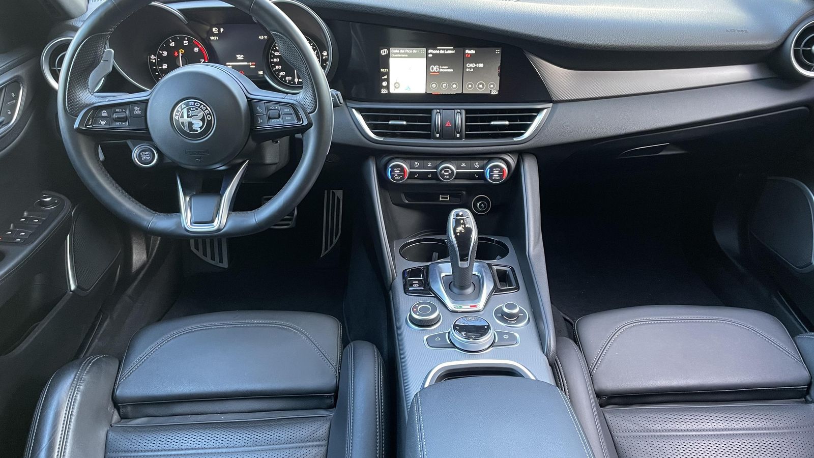 La pantalla central está ligeramente girada hacia el conductor. La elevada consola central hace que todos sus mandos queden muy a la mano y el volante tiene dos enormes levas para el manejo manual del cambio. También está ahí el botón de arranque.