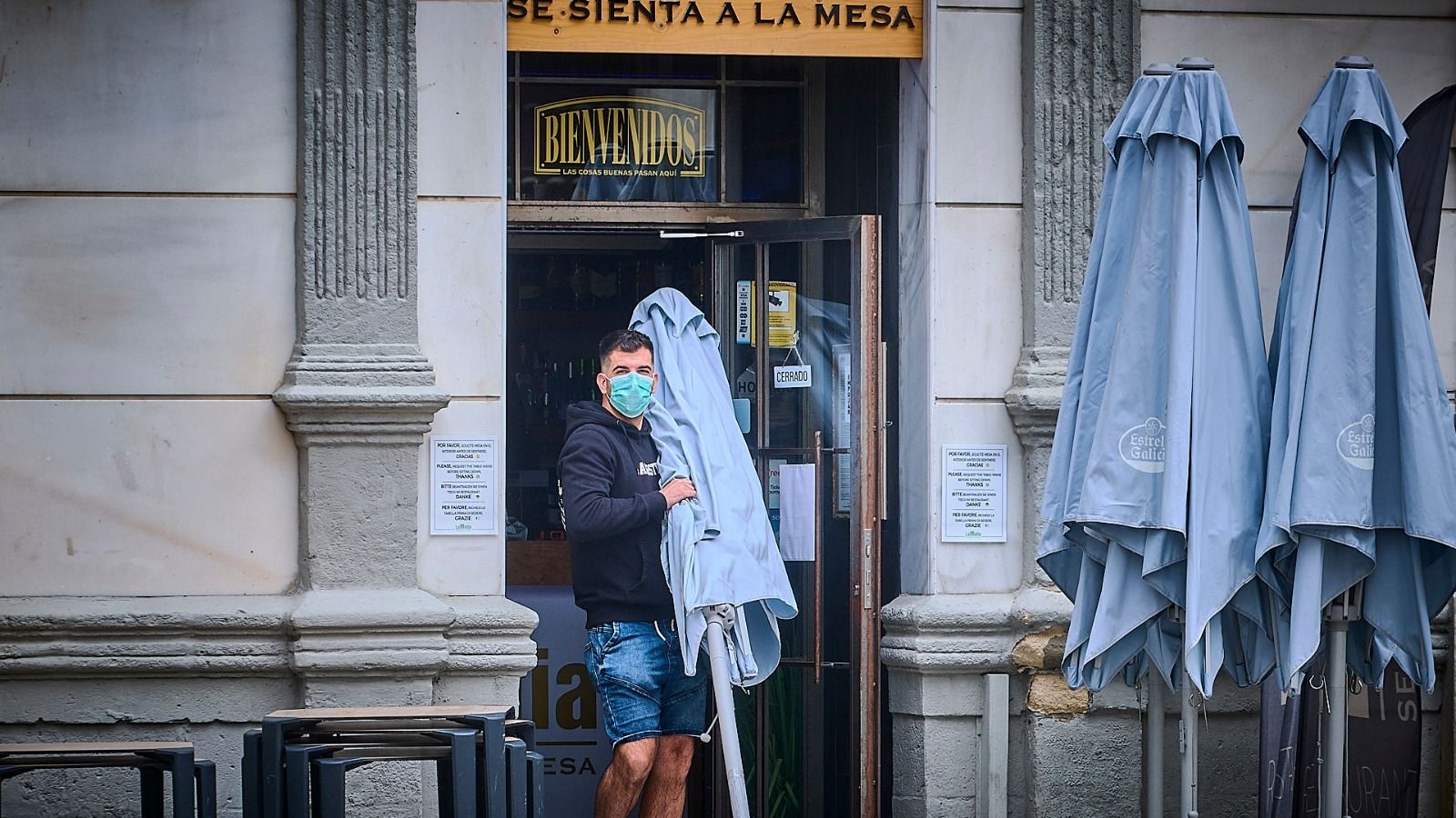 Un empleado saca una sombrilla de un local gaditano.