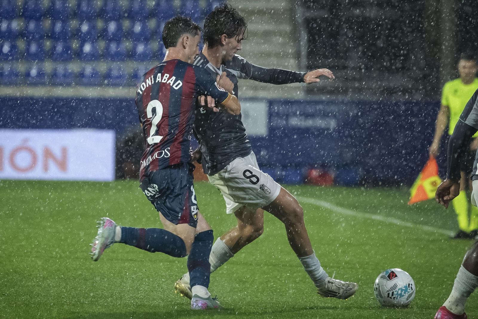 Alemañ protege el balón bajo la lluvia ante un jugador del Huesca