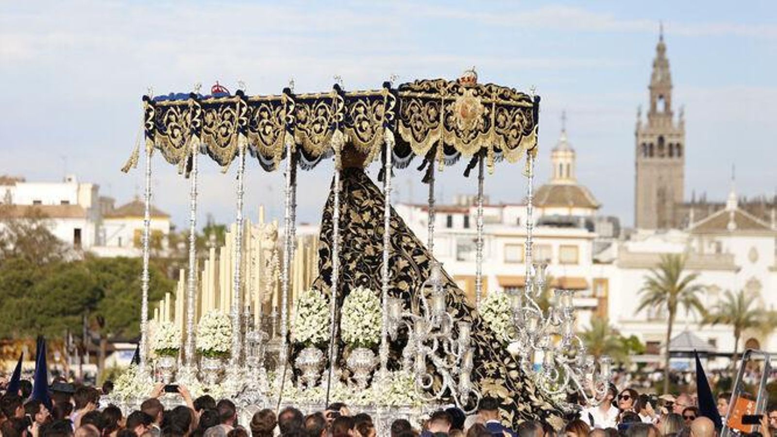 El palio de la Estrella, acompañada por la Oliva, cruza el puente de Triana