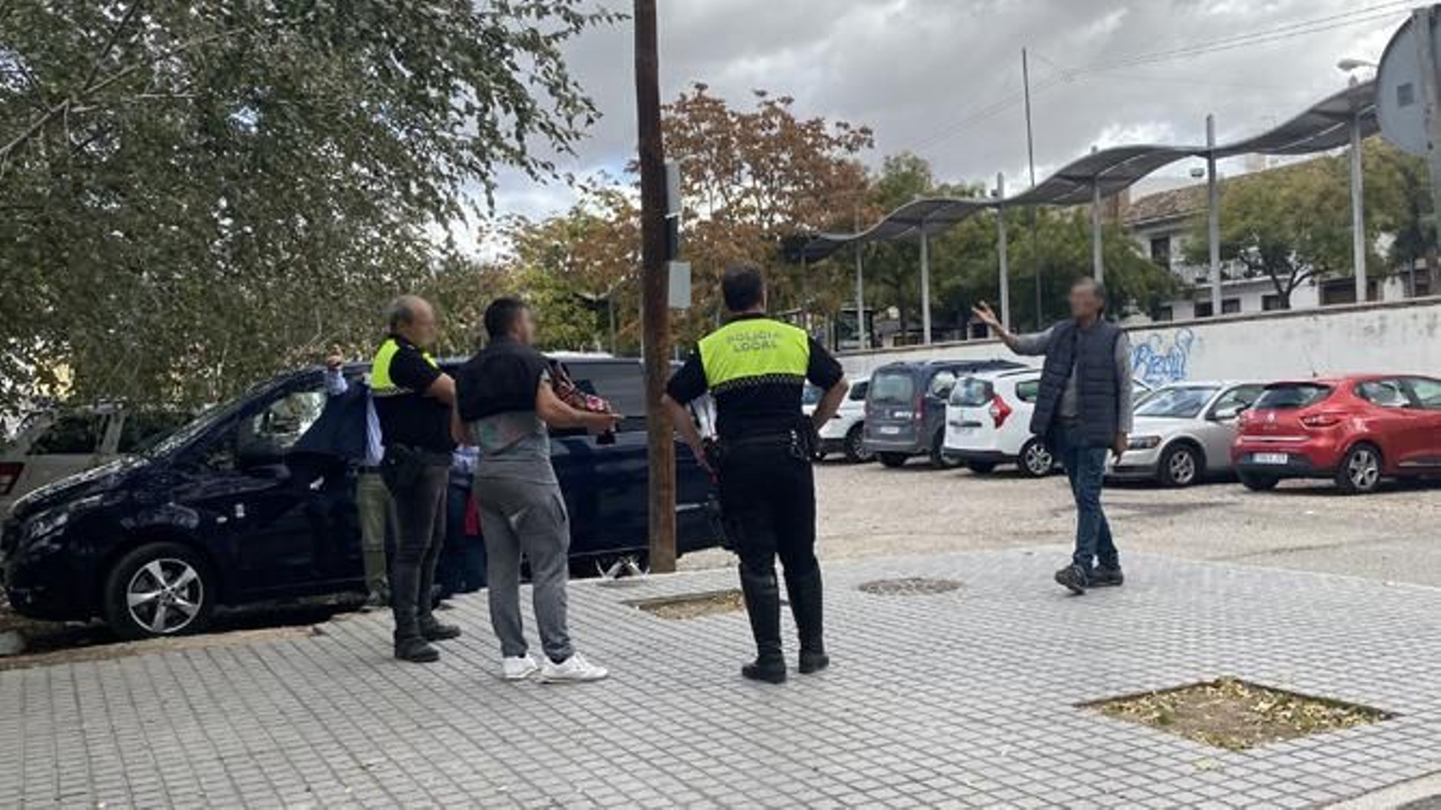 Dos agentes conversan con varios 'gorrillas' en la calle Nuestro Padre Jesús de los Reyes.