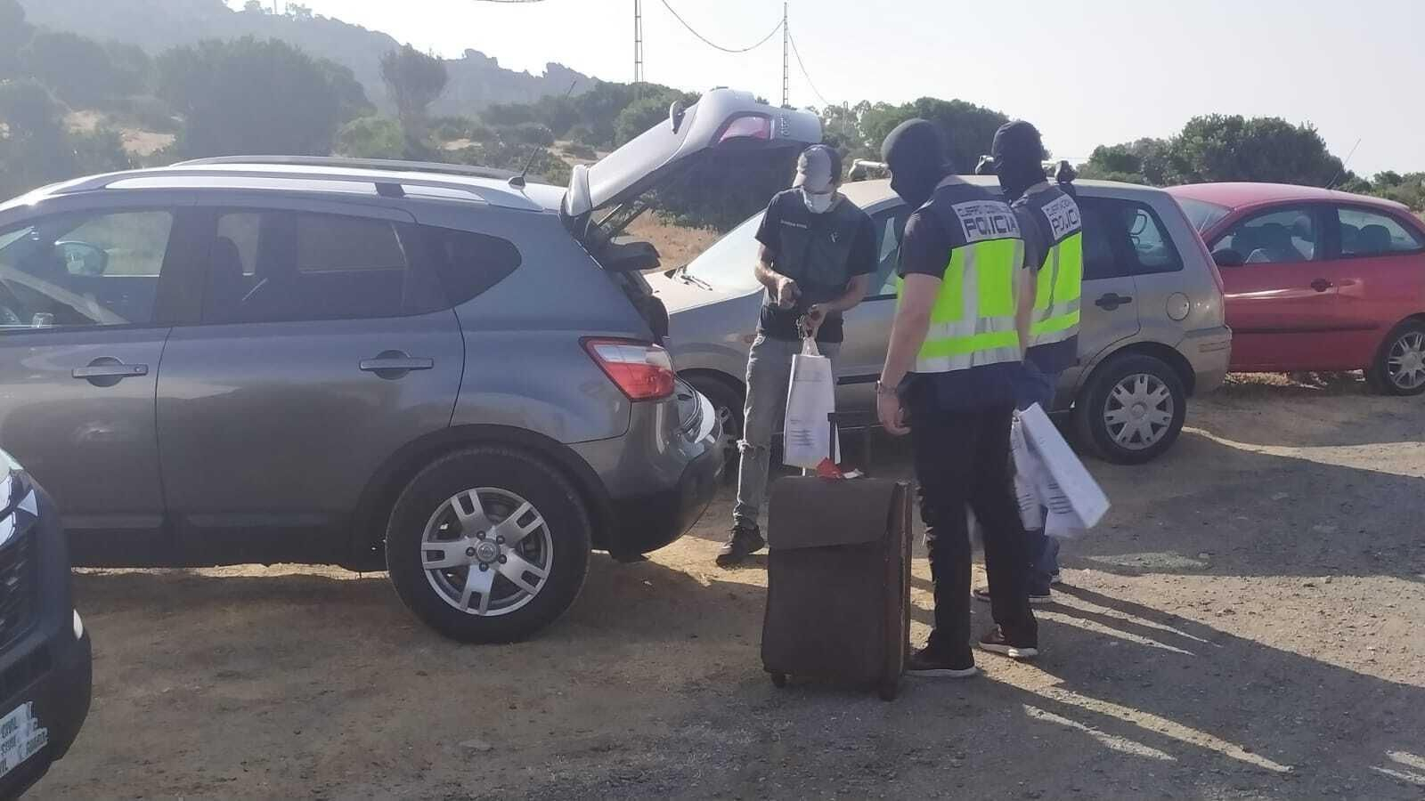 Un guardia civil y dos policías nacionales guardan bolsas tras uno de los registros.