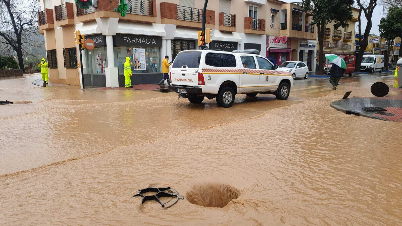 Tapas de alcantarilla levantadas para aliviar las balsas de agua en la calle José Calderón de Campanillas.