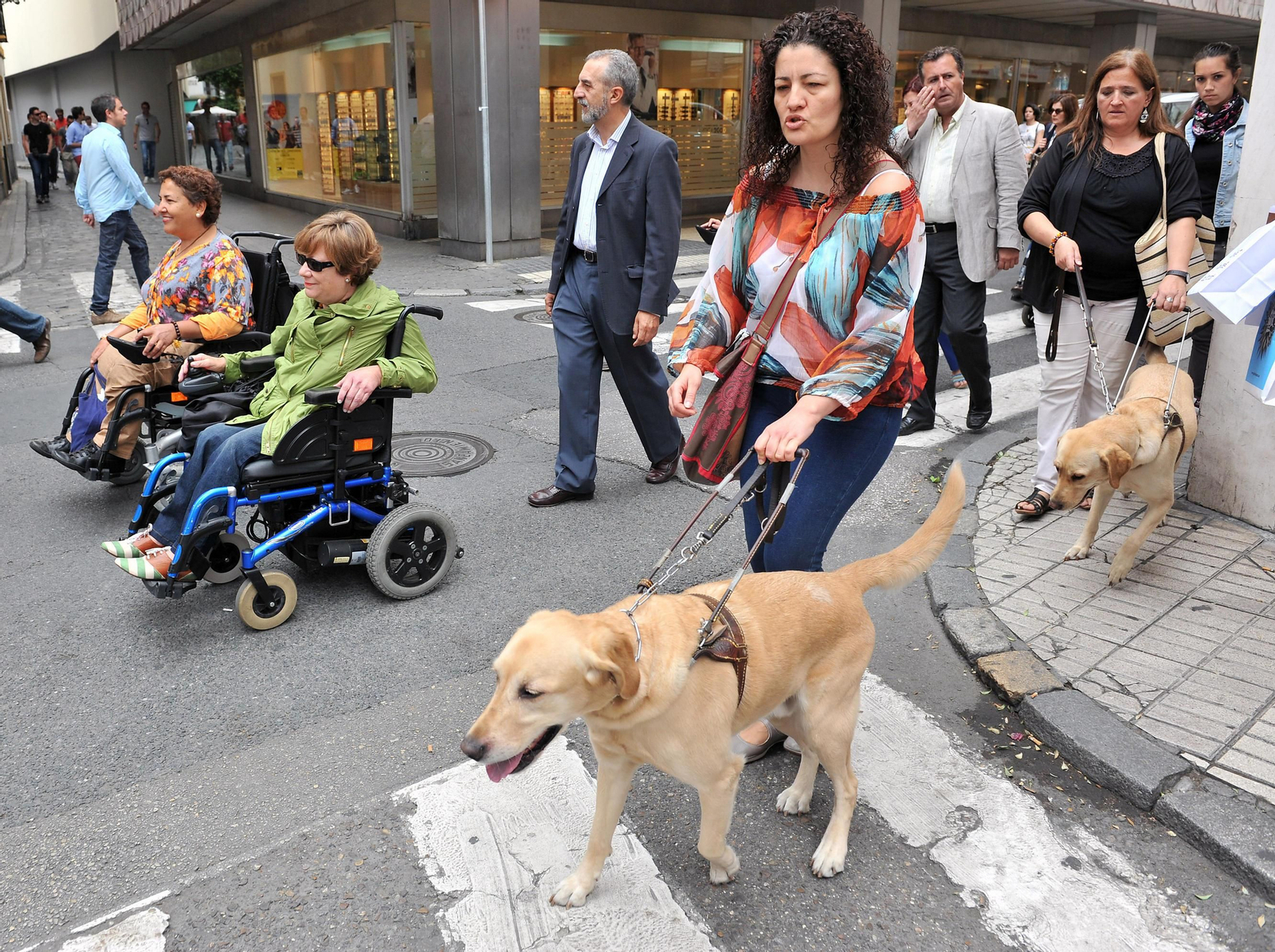 Un par de personas pasean por la calle con su perro de asistencia