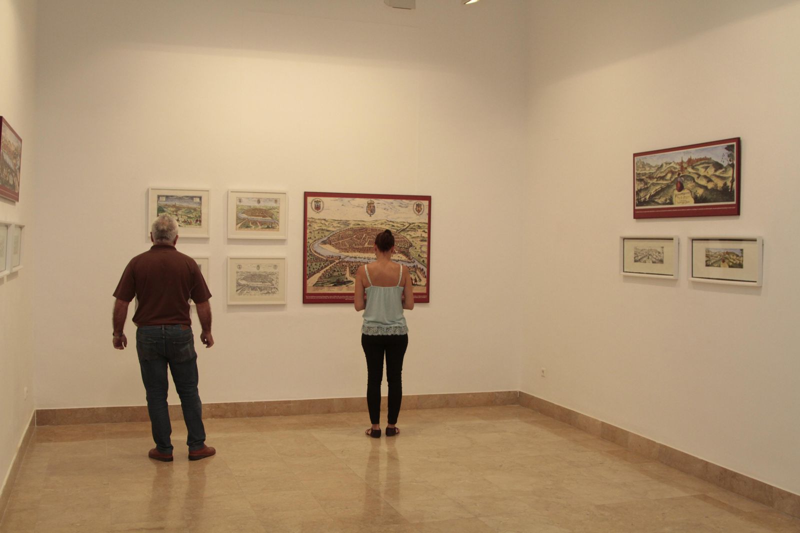 Una de las salas de la exposición. Abajo, uno de los paisajes, el dedicado a Écija, en el que se aprecia el interés del autor por las escenas costumbristas.