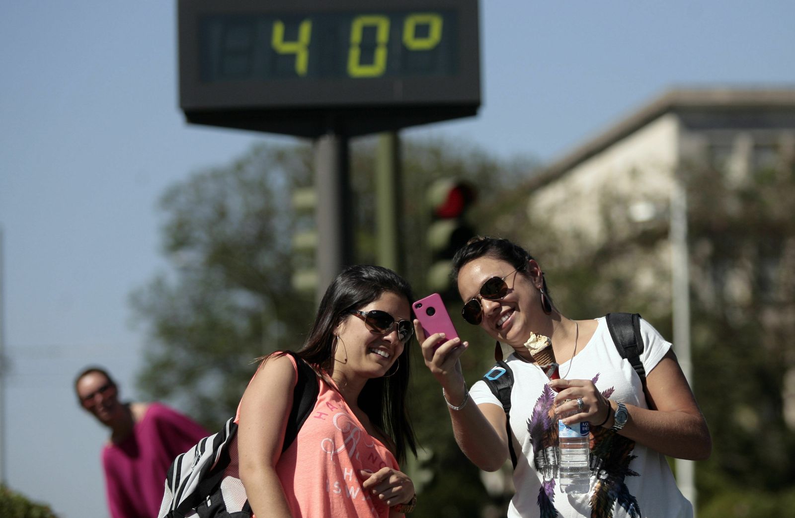 Dos jóvenes se hacen una foto ante un termómetro.