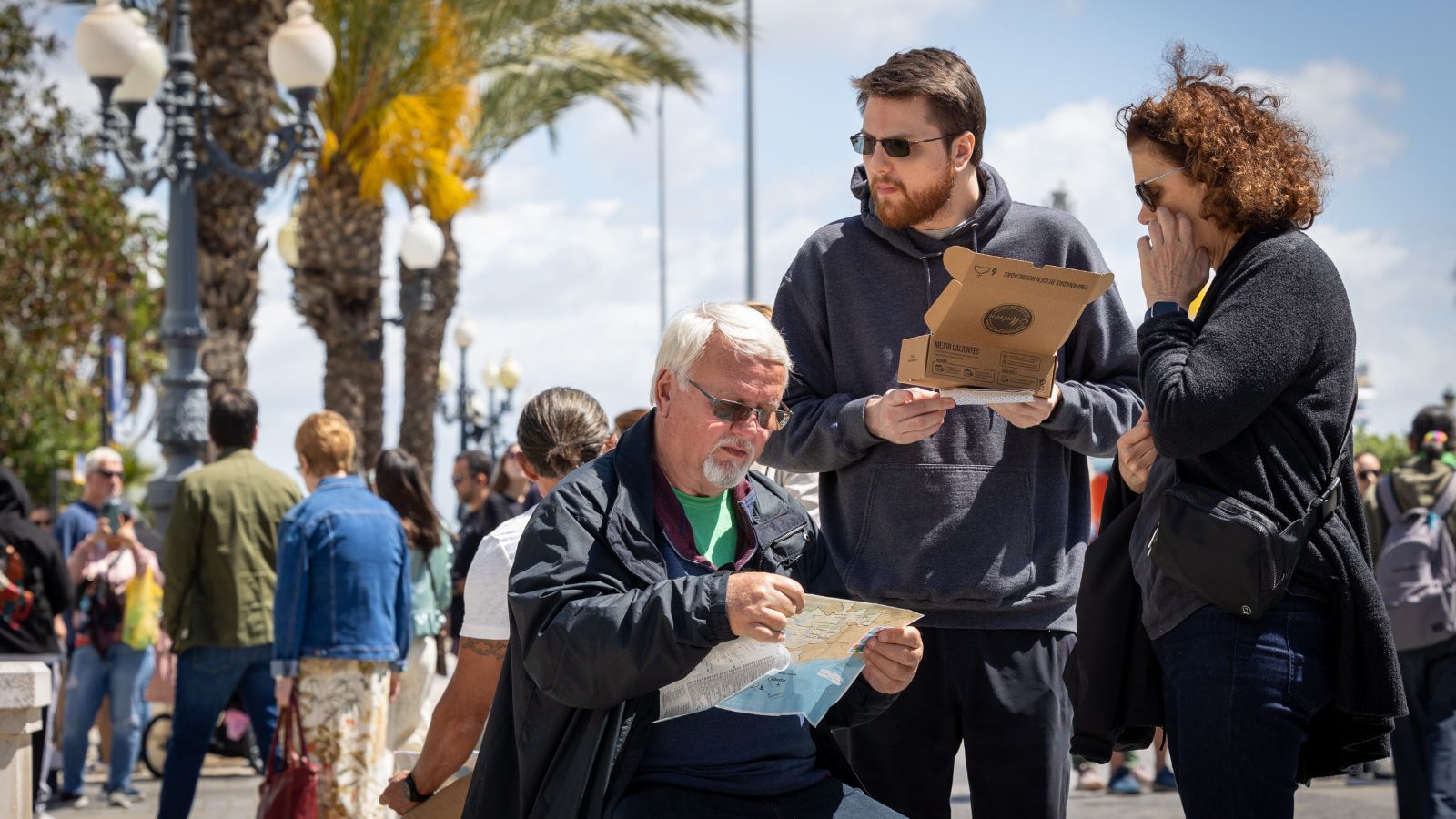 Un grupo de turistas llegados a Cádiz en crucero tratan de ubicarse en la ciudad mientras hacen un alto en el camino para comer algo