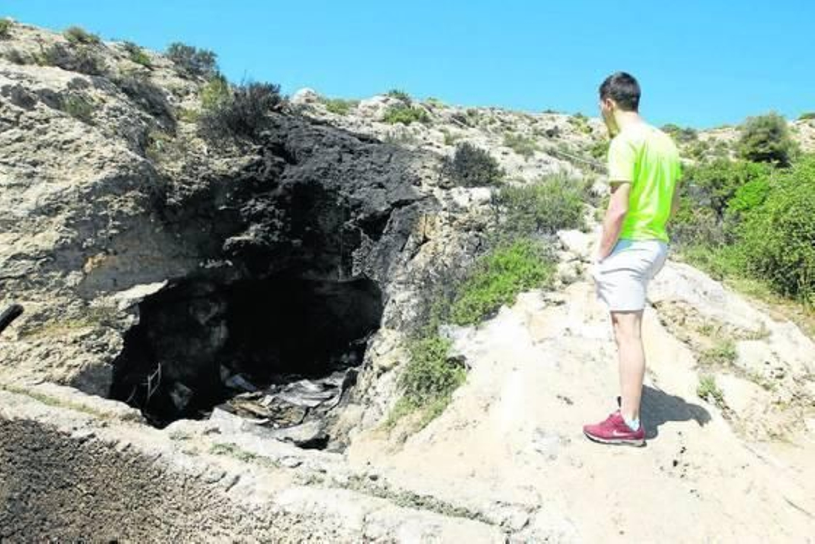 Un joven observa la cueva en los días siguientes al incendio.