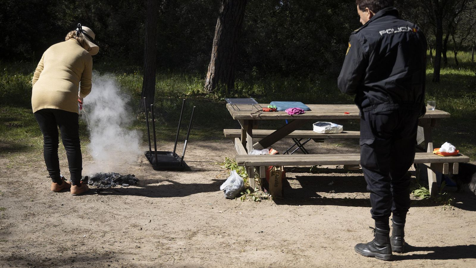 La mujer vierte agua sobre las brasas para apagarlas.