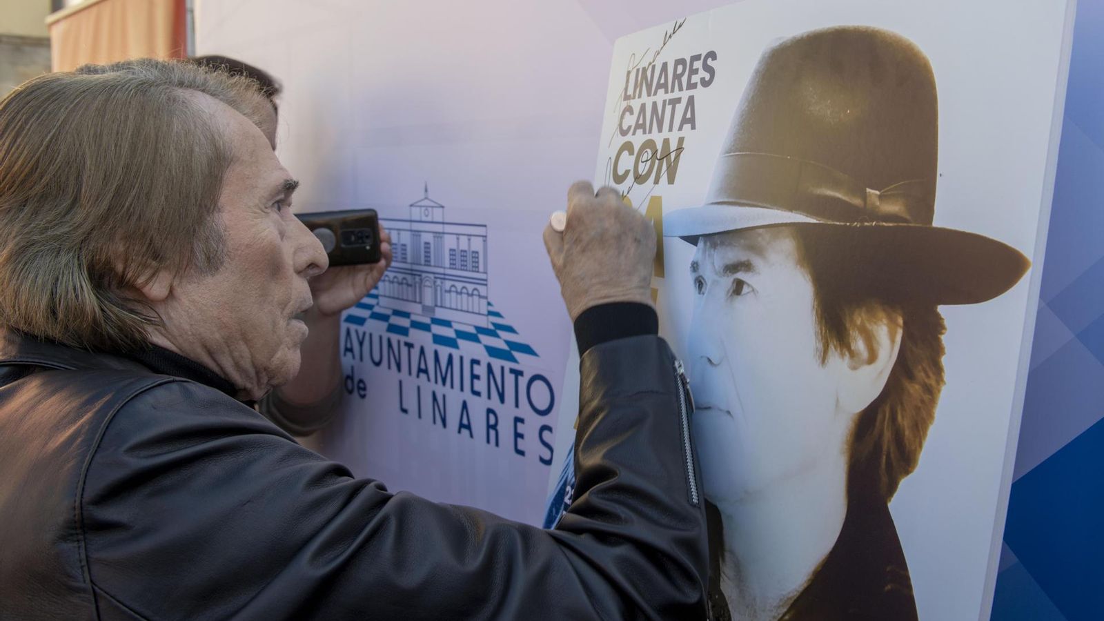 Raphael firma un cartel promocional en Linares.