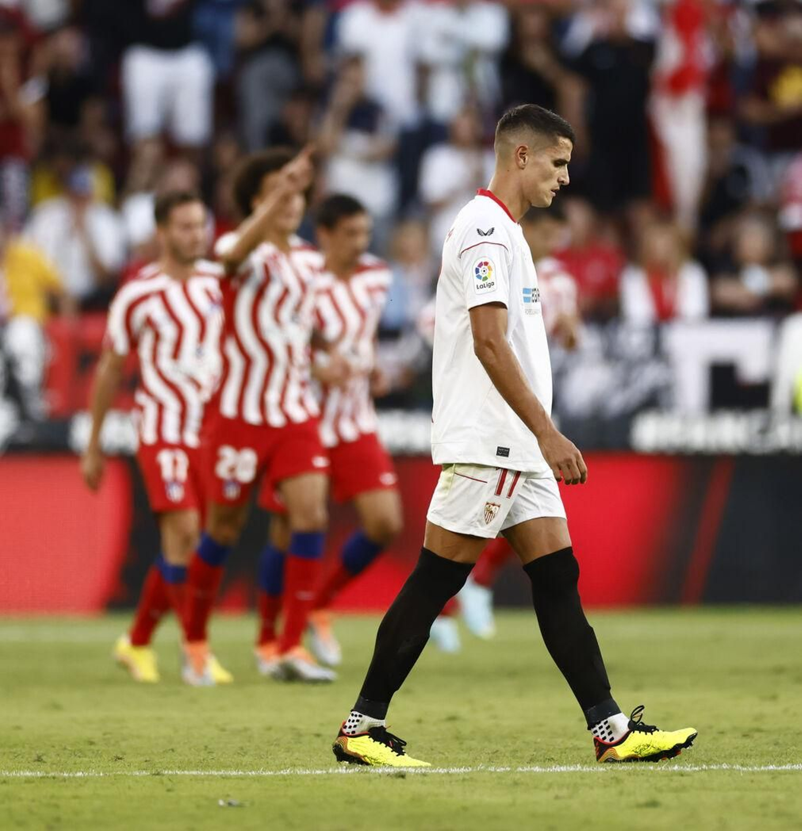 Lamela, cabizbajo mientras los jugadores atlético celebran uno de los goles.