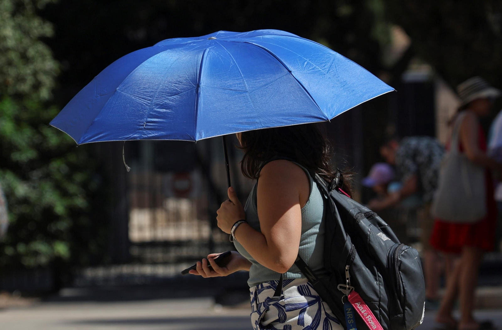Una mujer se protege del sol con un paraguas.