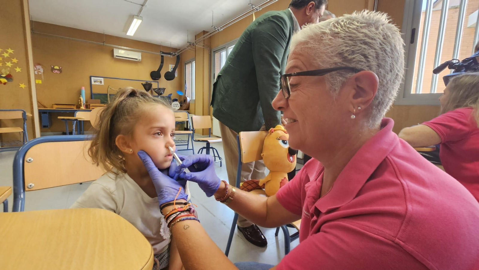 La enfermera referente vacuna a una niña que dice que la vacuna huele a fresa y está sorprendida porque no le ha dolido.
