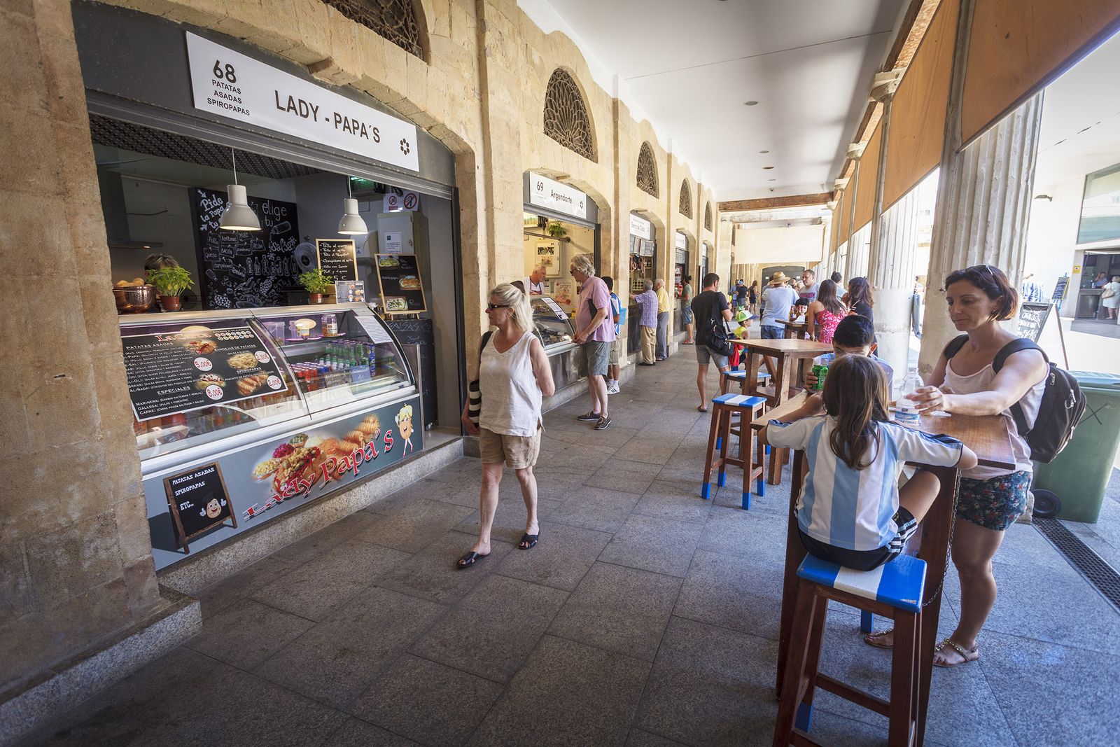 Varias personas compran diferentes productos en el Rincón Gastronómico del Mercado Central.