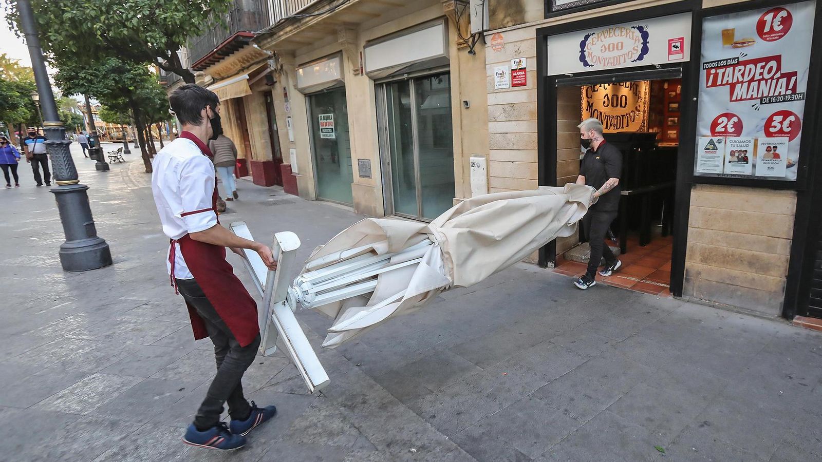 Recogida de los veladores de un bar del centro antes del nuevo horario de cierre a las seis de la tarde.