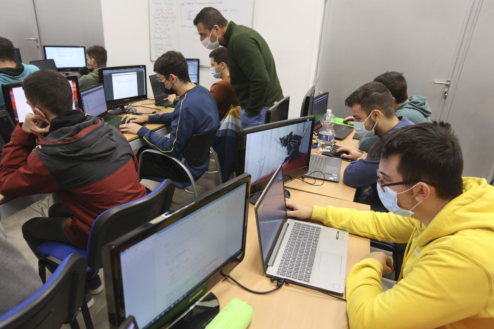 Un profesor revisa las actividades de alumnos de Formación Profesional.