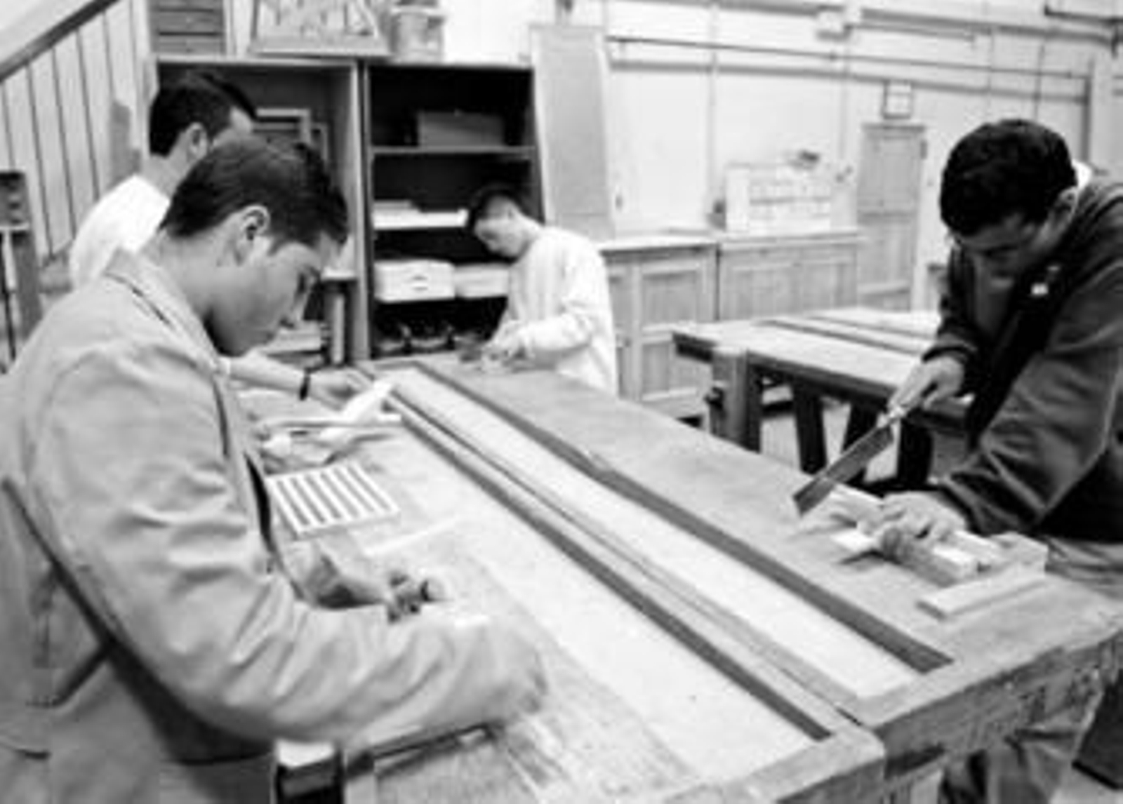 Unos jóvenes trabajan en la construcción de un mueble en una fábrica cordobesa.