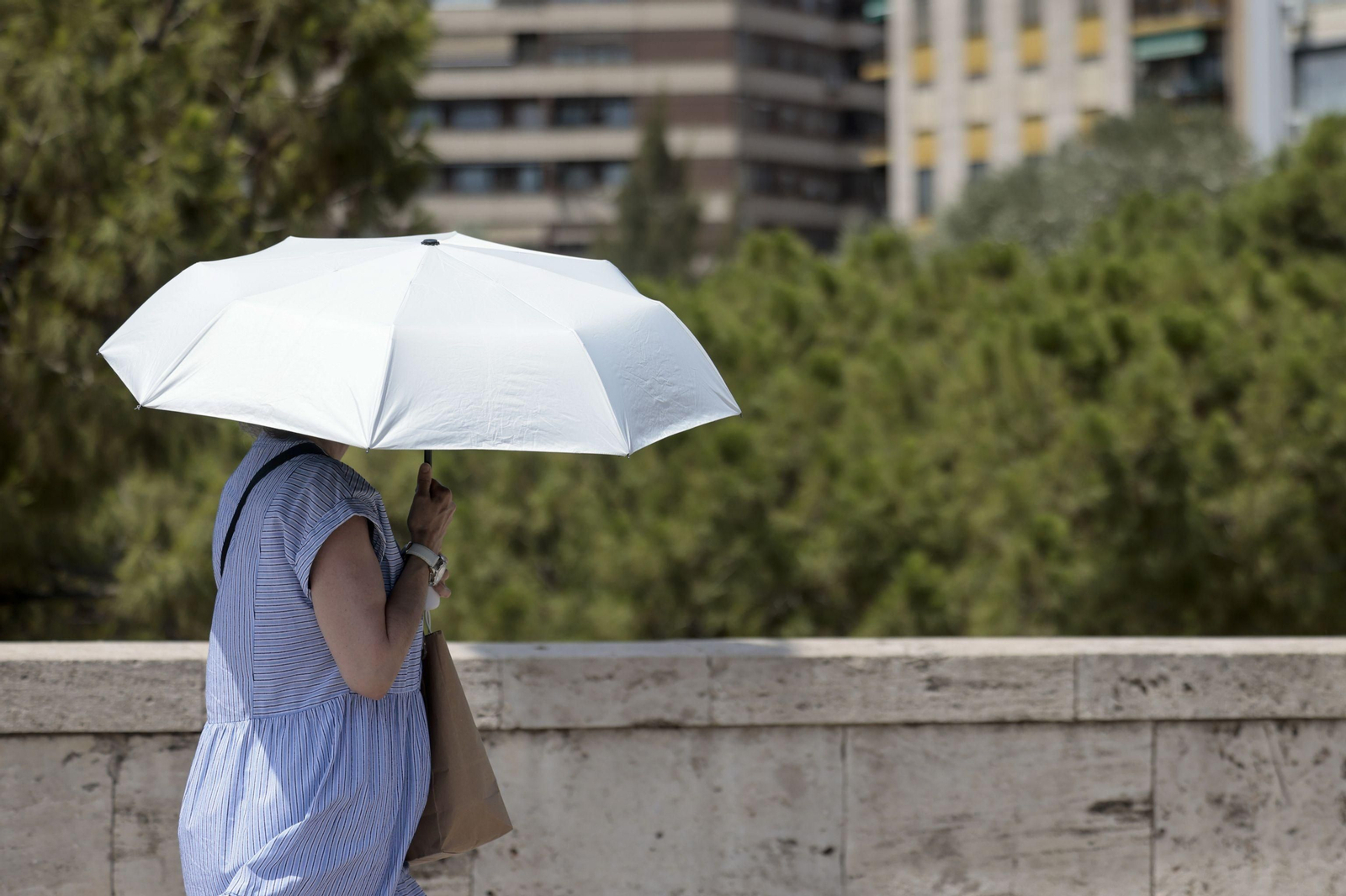 Una mujer se protege del sol con una sombrilla.