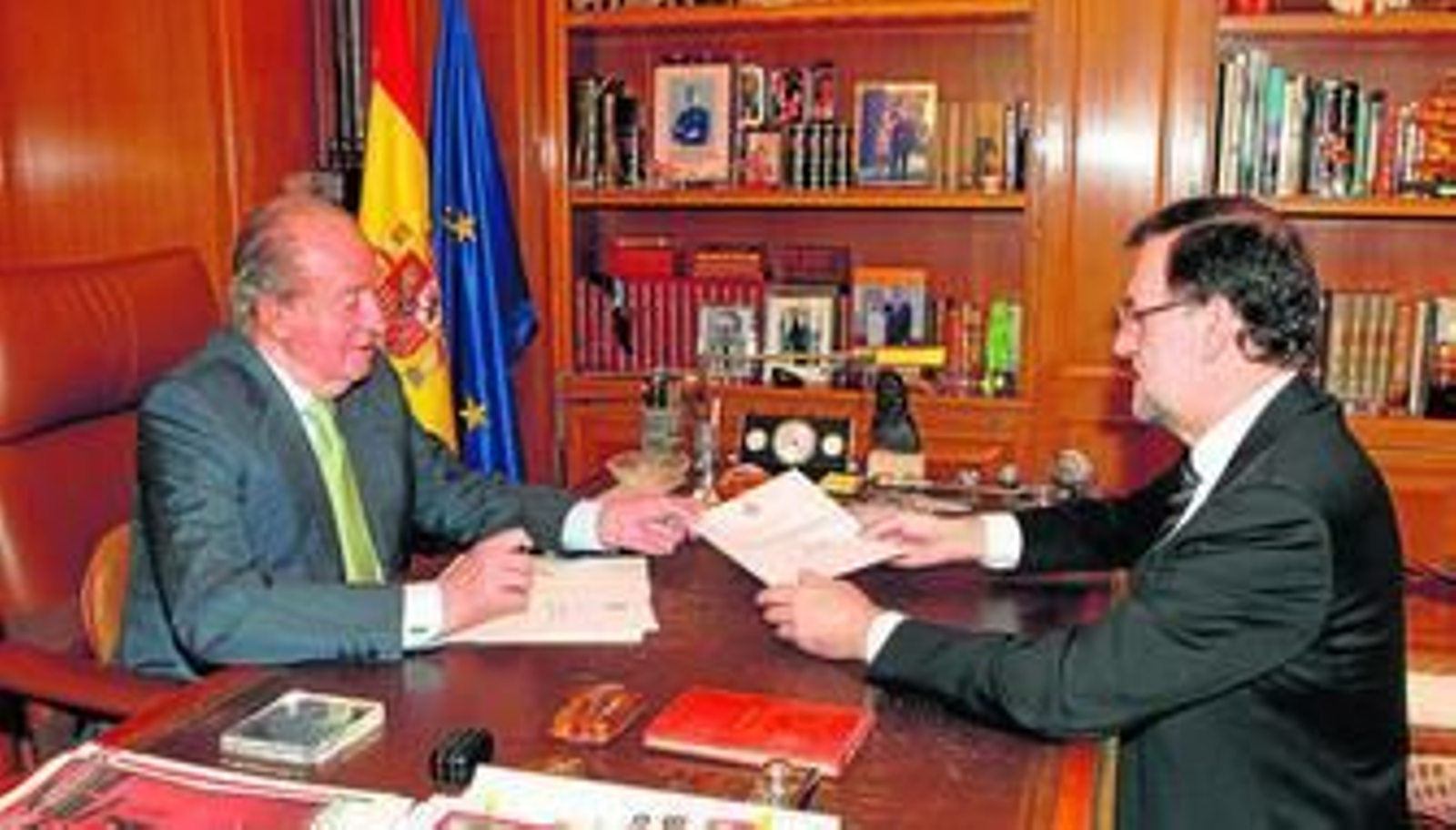 El rey Juan Carlos entrega el documento de su abdicación al presidente del Gobierno, ayer en el Palacio de la Zarzuela.