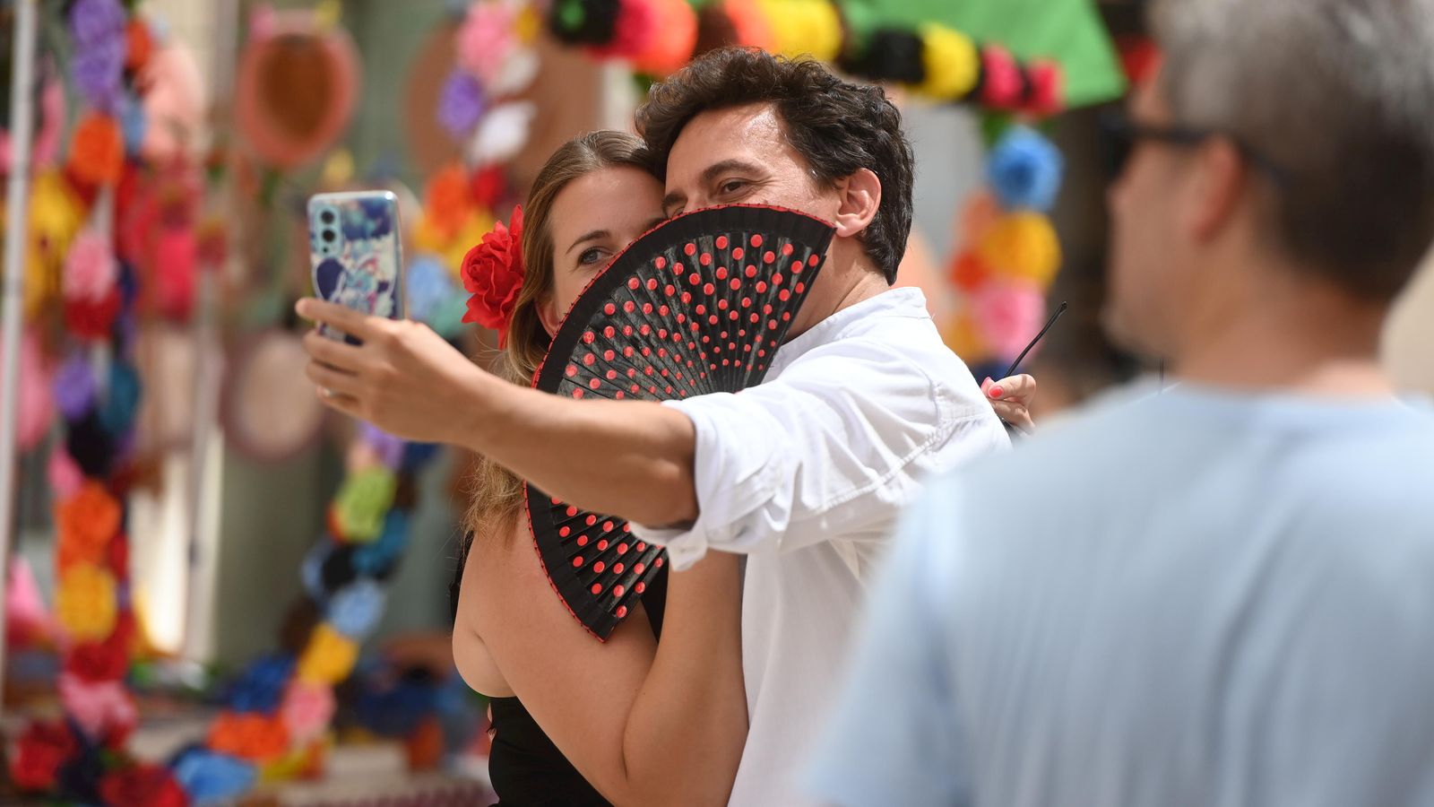 Una pareja se hace un selfie con un abanico de lunares.