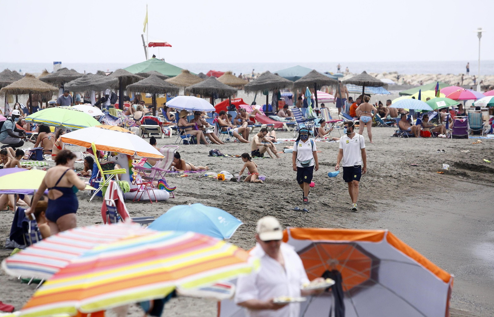 Dos asistentes en la playa de Pedregalejo, junto a los bañistas, este domingo.